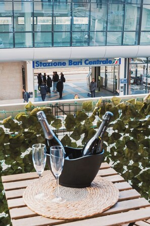 A view of a restaurant entrance with people walking in and out, a bottle of champagne on a table, and a view of a building with large windows. - APULIA ROOMS BARI (Bari)