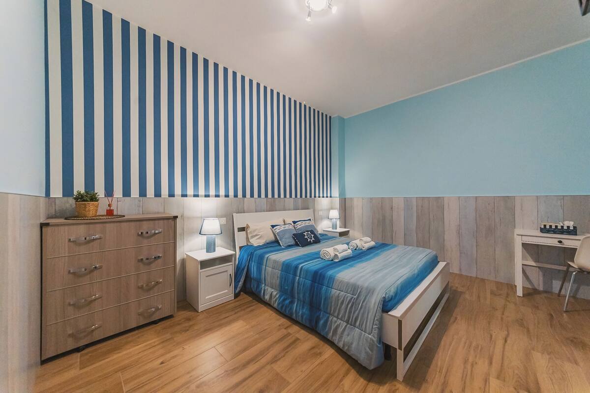 A bedroom with a bed, bedside tables, a desk, and a wardrobe.