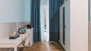 Cucina compatta con piano di lavoro in legno, mobiletto bianco e finestra con tende blu.