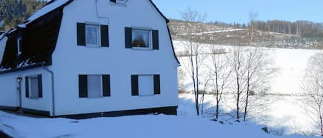Ein weißes Haus mit einem steilen Dach, einer Satellitenschüssel und einem kleinen Fenster.