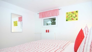 Une chambre à coucher avec un lit, une fenêtre, un radiateur et un miroir.