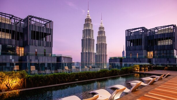 Zona de piscina en la azotea con sillones de descanso y vistas a las Torres Petronas.