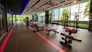 Un gimnasio con equipo de ejercicio, ventanas amplias y una línea roja en el suelo.