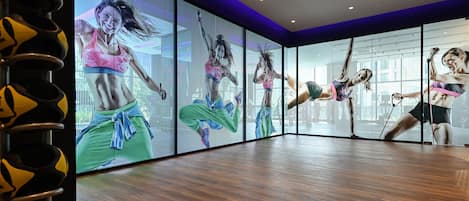 A fitness studio with mirrored walls, wooden flooring, and exercise equipment.