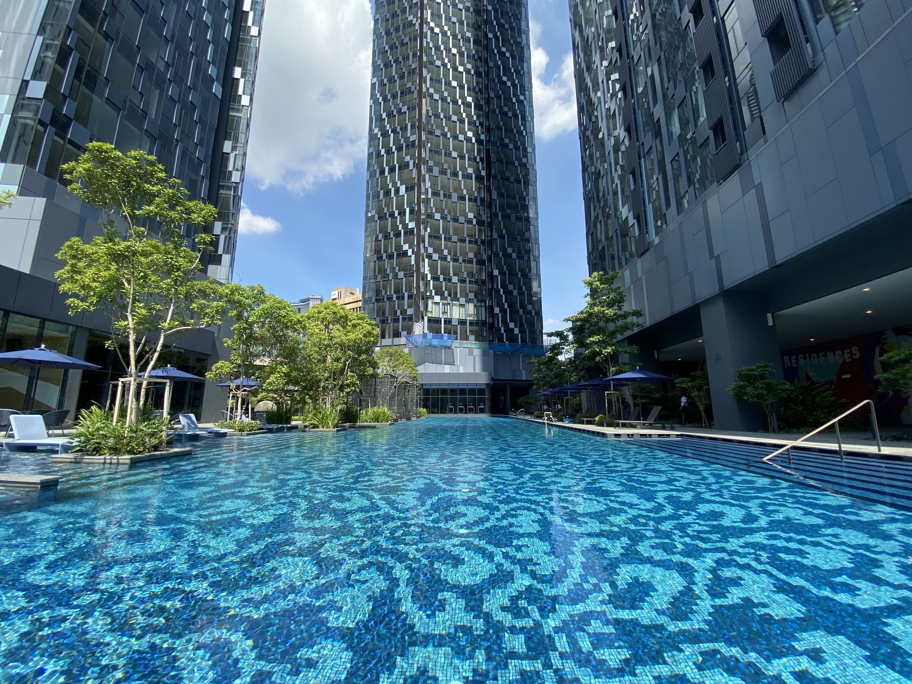 Una piscina rodeada de edificios modernos y árboles.