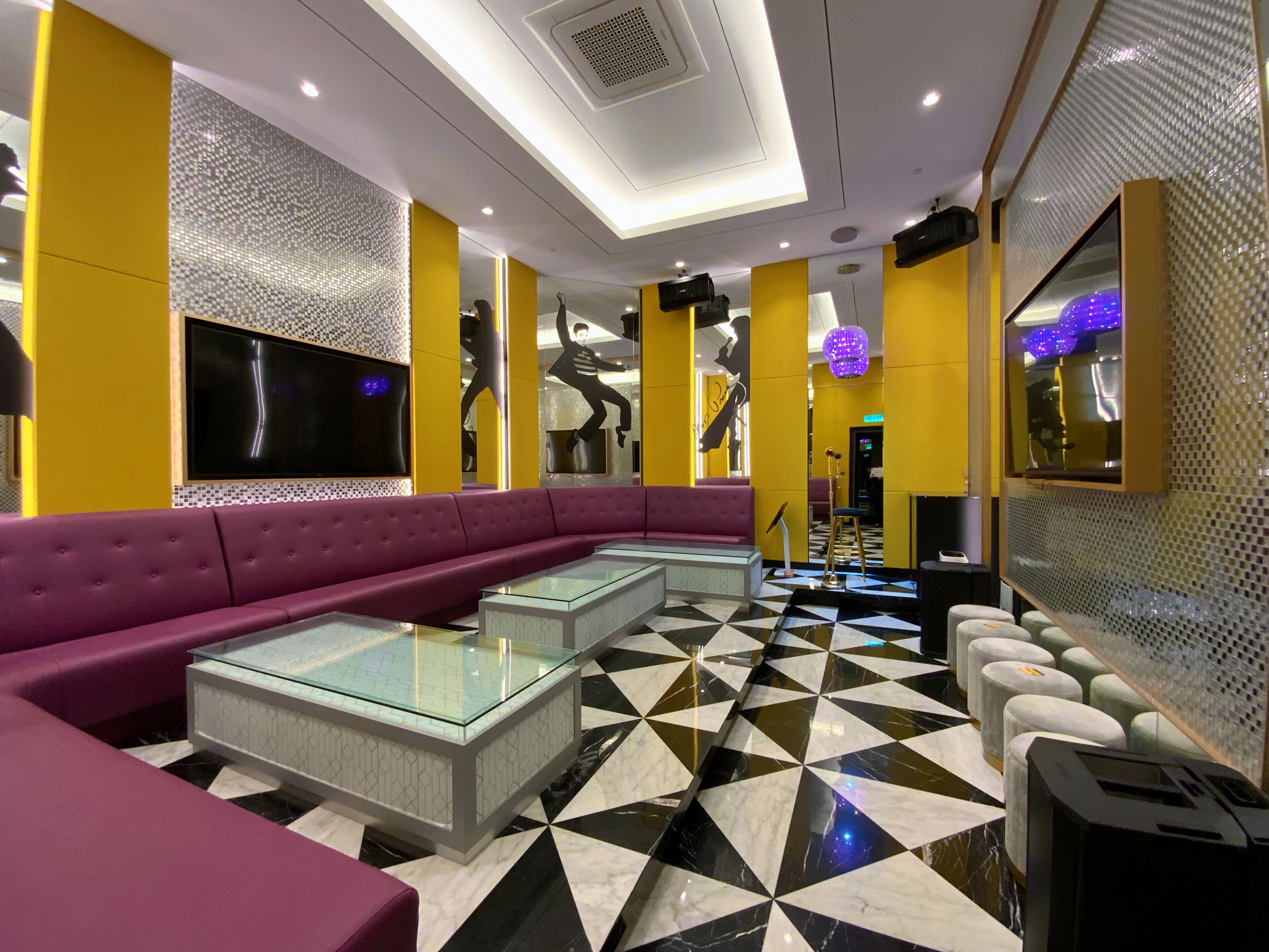 Eine moderne Hotelhalle mit einem großen violetten Sofa, Glastischen und einem schwarz-weißen Fußboden.
