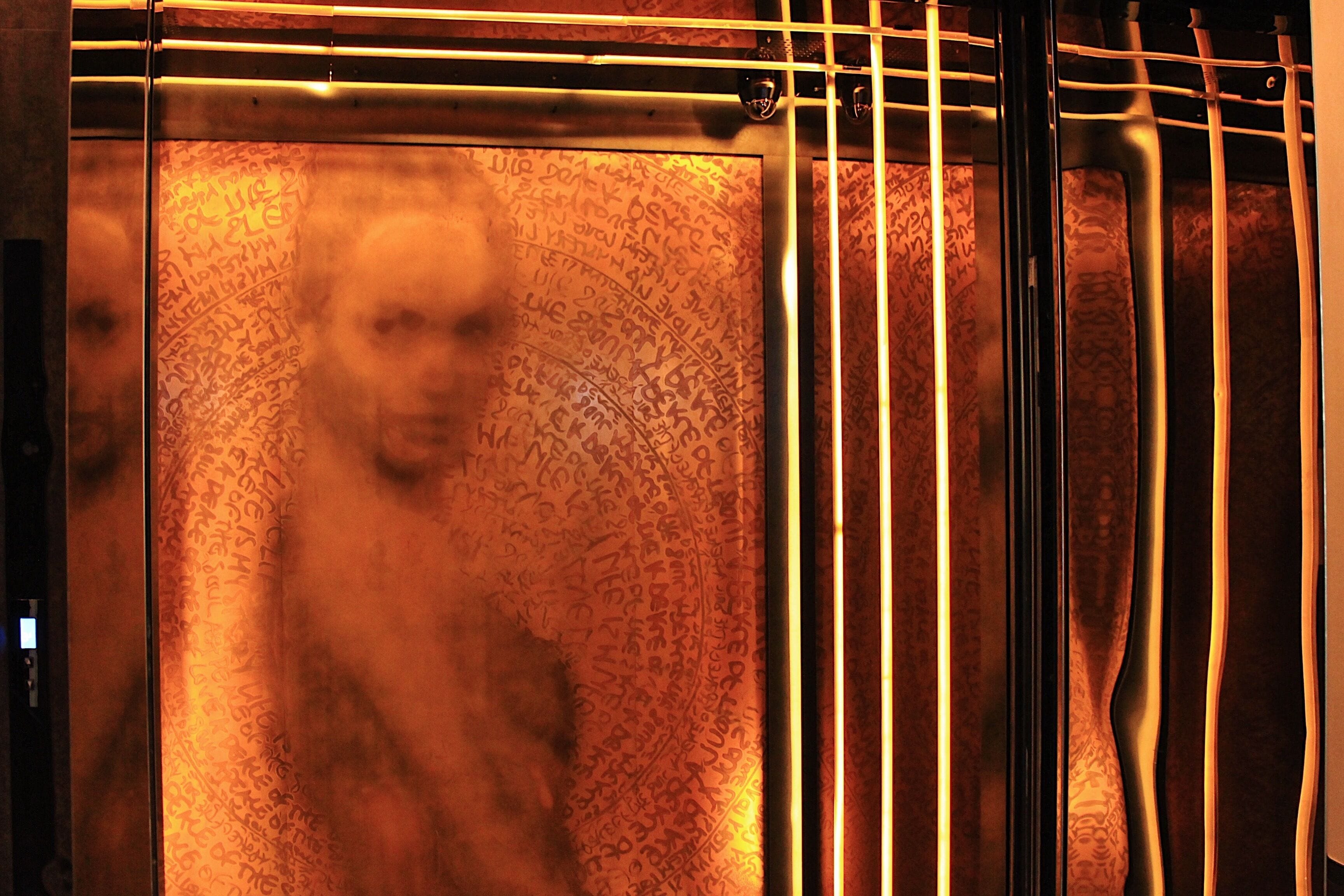 An elevator interior with graffiti on the walls.