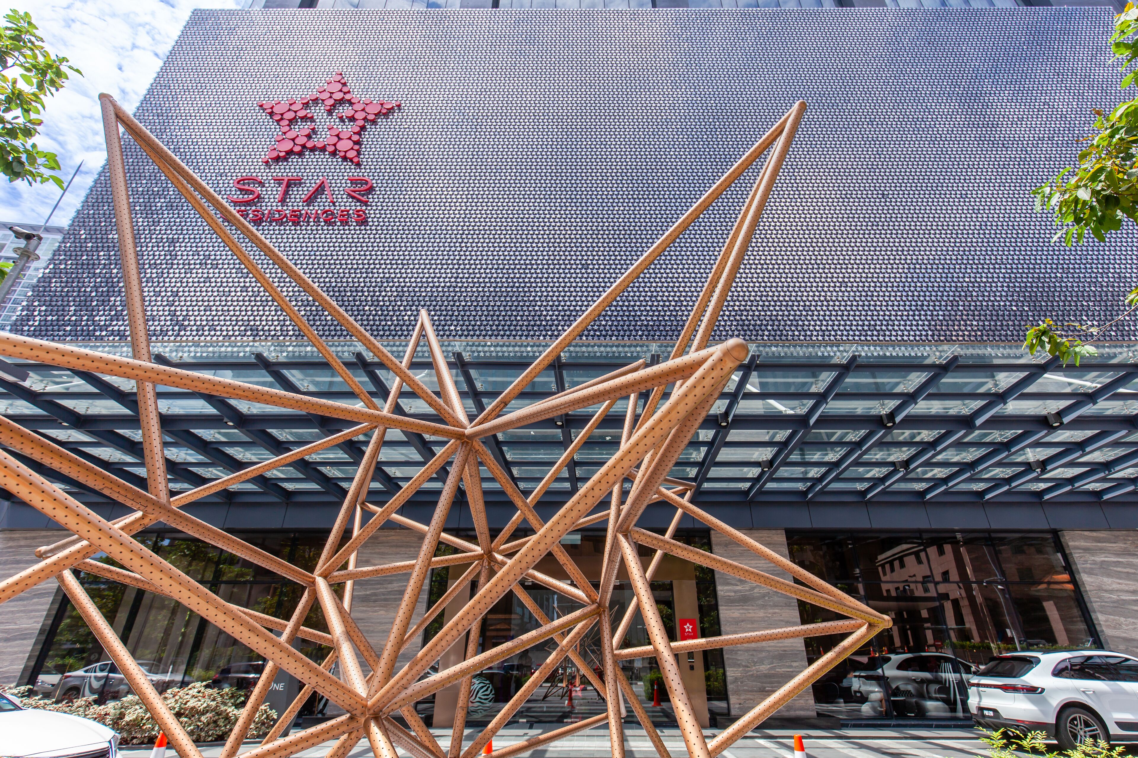 Un edificio moderno con un llamativo logo de estrella y una escultura metálica geométrica en primer plano.