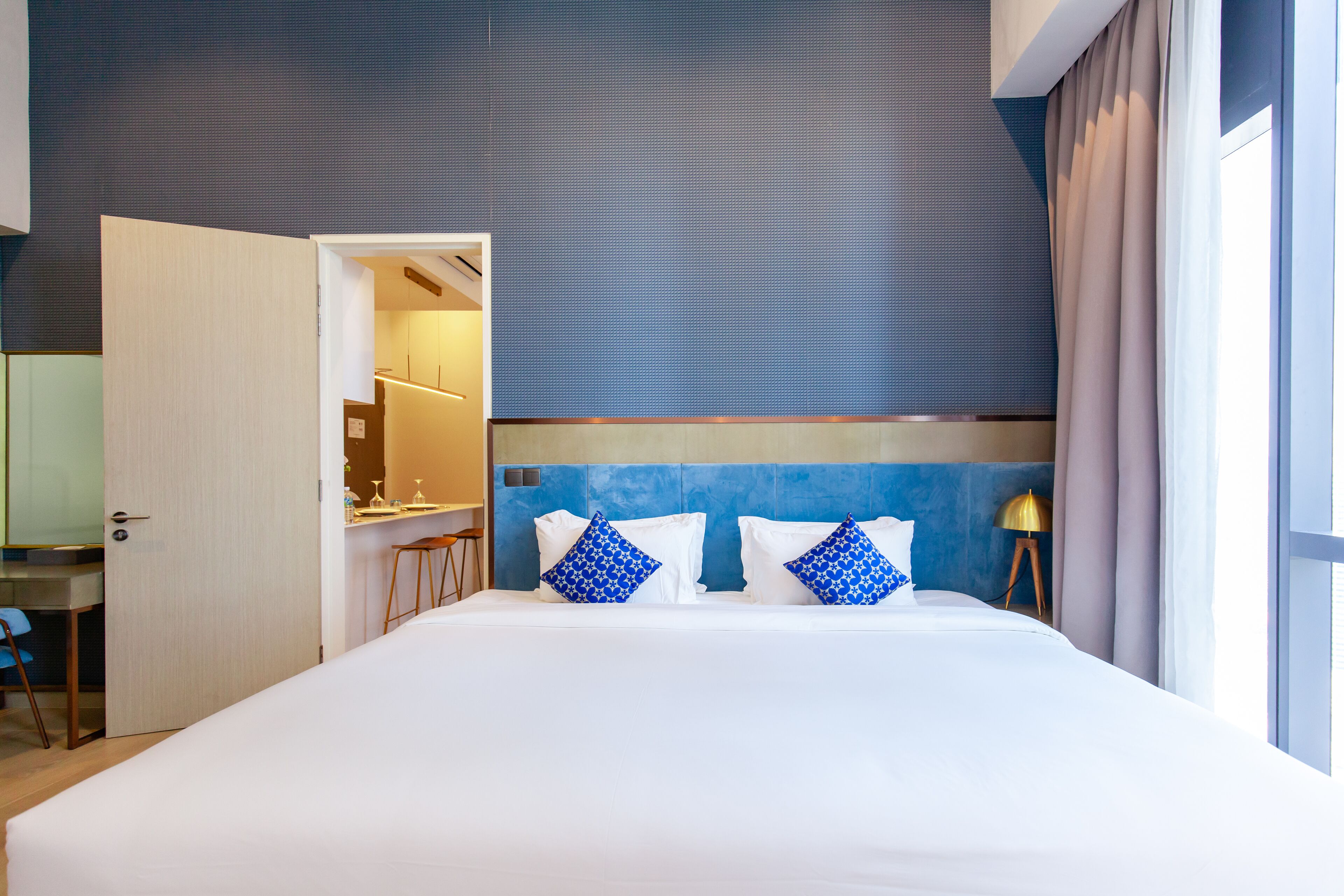 A hotel room with a large bed, two pillows, a desk, and a chair.
