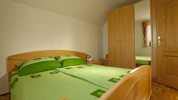 Un dormitorio con cama de madera, ropa de cama verde, una mesita de noche y un armario.