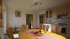Een keuken met houten kastjes, een betegelde achterwand en een eettafel met geruit tafelkleed.