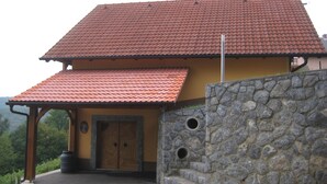 Een gebouw met twee verdiepingen, een rode dakbedekking van pannen en een stenen muur.