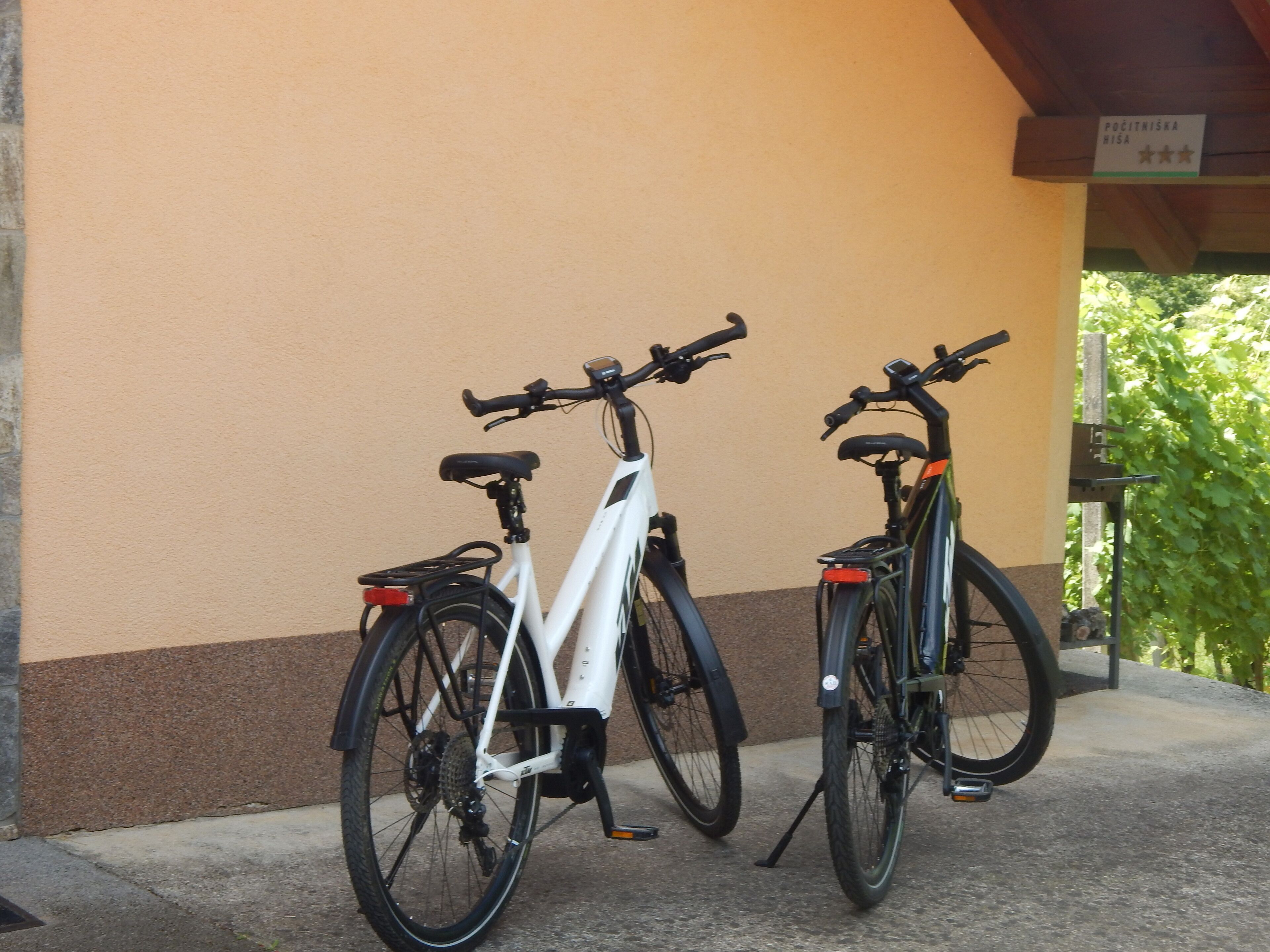 Two bicycles parked against a wall with a sign above them.
