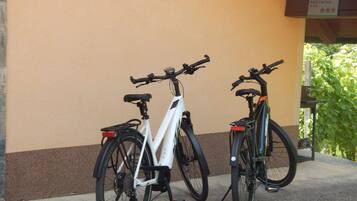 Two bicycles parked against a wall with a sign above them.