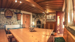 Un intérieur rustique avec une table en bois, des murs en pierre, une cheminée et un plafond en bois.