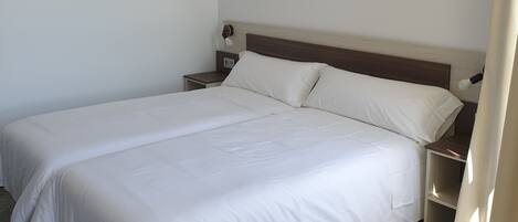 Un lit double avec du linge de lit blanc dans une chambre d’hôtel.