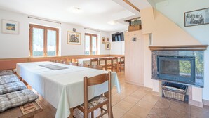 A dining area with a long table, chairs, and a fireplace. - Vineyard cottage Vrbekova gorca (Šmarje pri Jelšah)