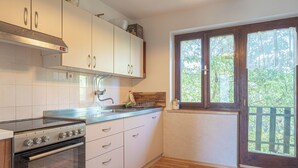 A kitchen with white cabinets, a stove, and a window with a view of greenery. - Vineyard cottage Vrbekova gorca (Šmarje pri Jelšah)