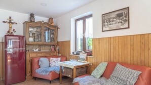 A cozy living room with a red refrigerator, a wooden cabinet, a red sofa, and a table with a lace tablecloth. - Vineyard cottage Vrbekova gorca (Šmarje pri Jelšah)
