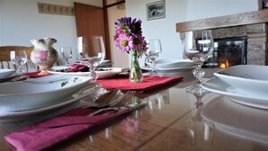 A dining table set with plates, glasses, and a vase of flowers. - Vineyard Cottage Zajc (Semic)