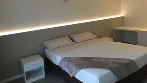 A bedroom with a bed, bedside tables, and a built-in bench. - Villa Rossa Dependance Lake Garda Bardolino-Cavaion (Dependance) (Cavaion Veronese)