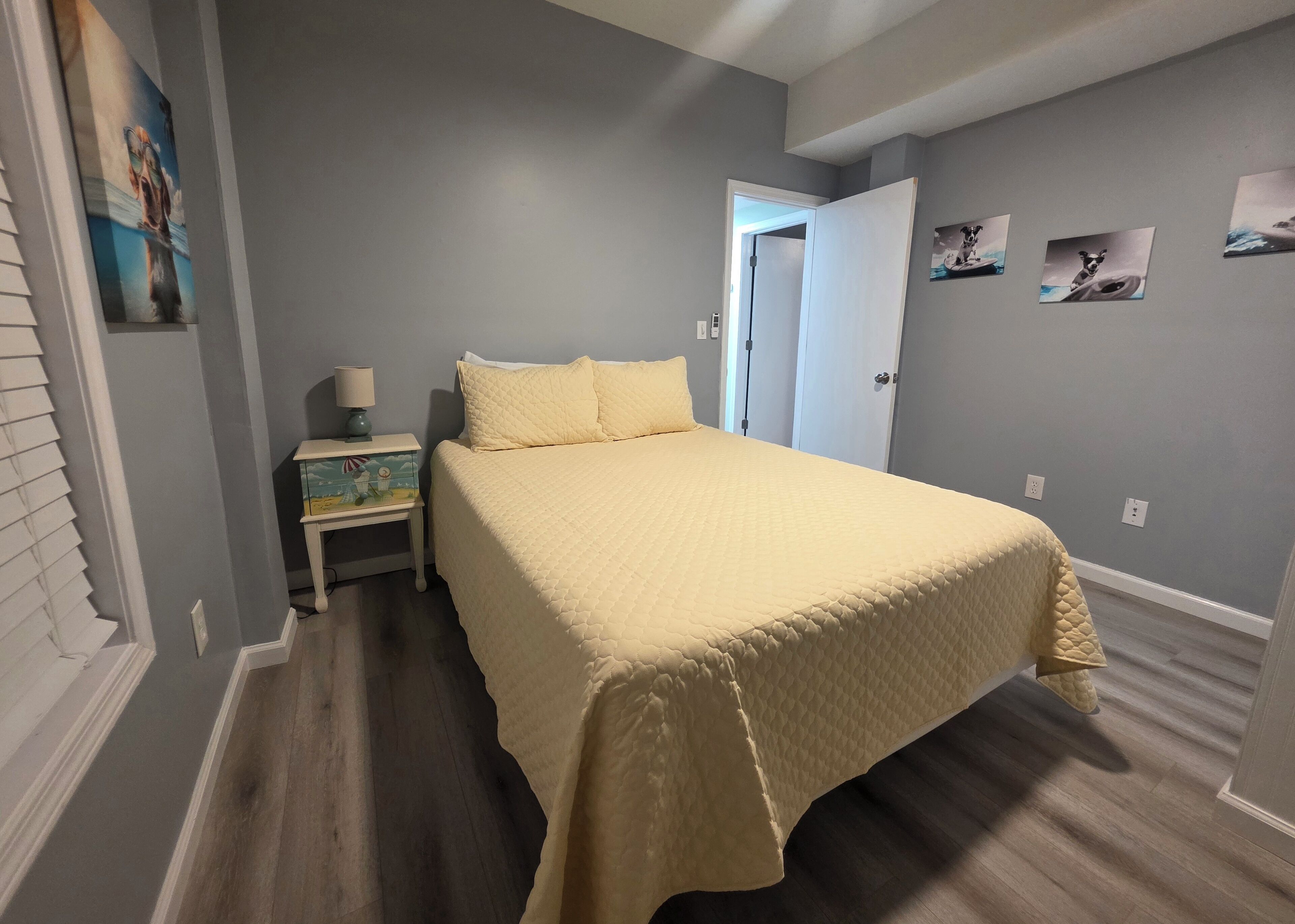 Un dormitorio con cama, mesita de noche y puerta que da a otra habitación.