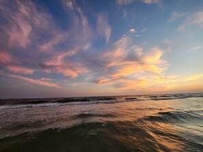 A beach with waves and a sunset sky.