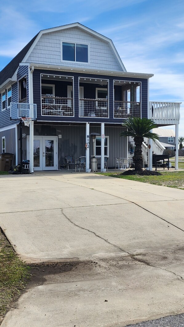 A two-story building with a balcony, a garage, and outdoor seating.