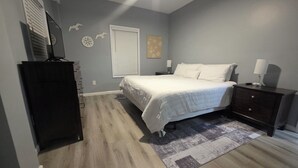 Quarto com cama, mesas de cabeceira, cómoda, tapete e decorações nas paredes.