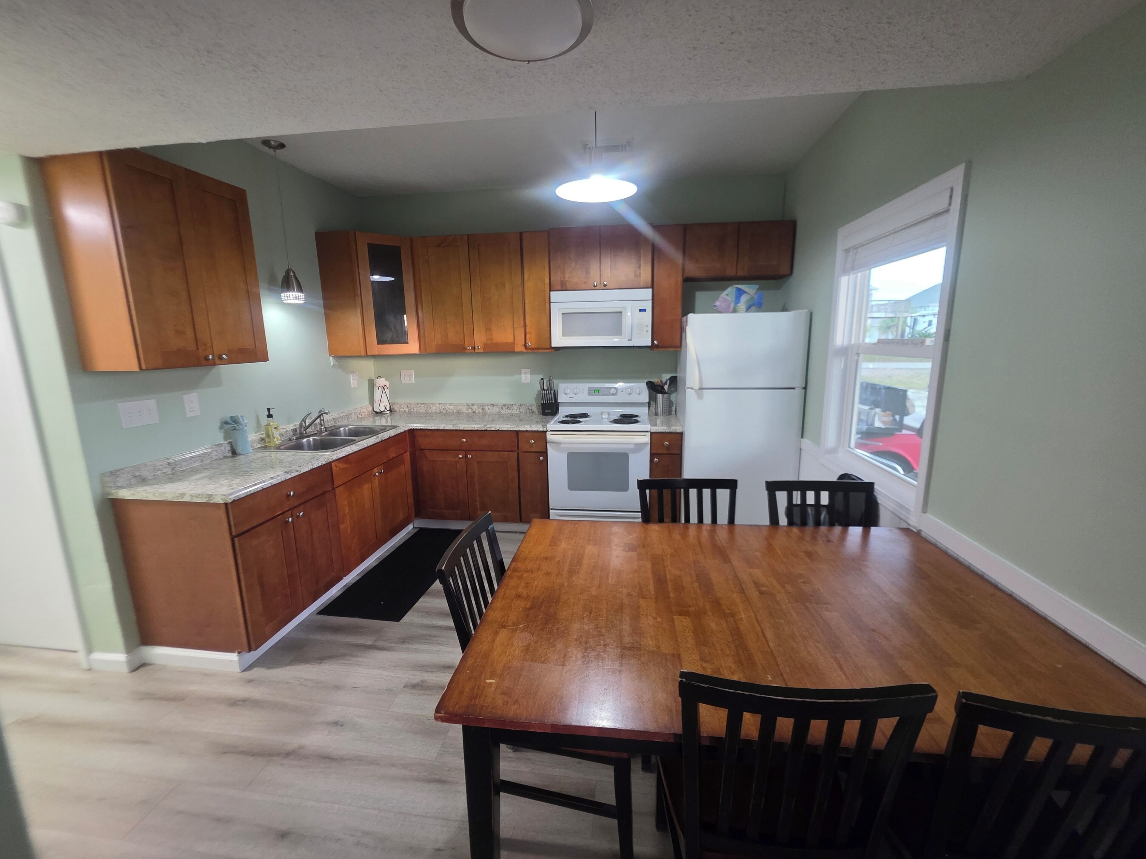 A kitchen with wooden cabinets, a white stove, and a dining table with chairs.