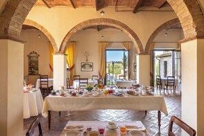 Ein Essbereich mit gedeckten Tischen zum Frühstück, gewölbten Ziegeldecken und Blick durch die Fenster.