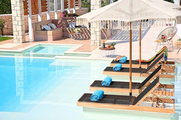 A poolside area with sun loungers, a seating area, and a covered umbrella.