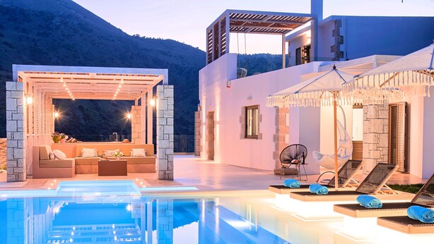 Un área de piscina exterior moderna con zona de estar y sillones reclinables.