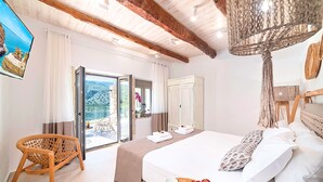 Habitación de hotel con una cama, una silla de mimbre, un frutero y vistas al exterior.