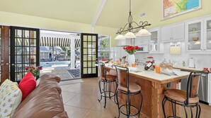 A spacious kitchen with a wooden island, bar stools, and a view to the outside.