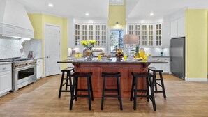 A modern kitchen with a central island, bar stools, a large refrigerator, and a stove.