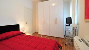 A bedroom with a bed, a wardrobe, a heater, and a television. - Red House ai Mori (Venice)
