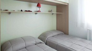 A bedroom with two beds, a shelf with decorative items, and a red lamp. - Red House ai Mori (Venice)