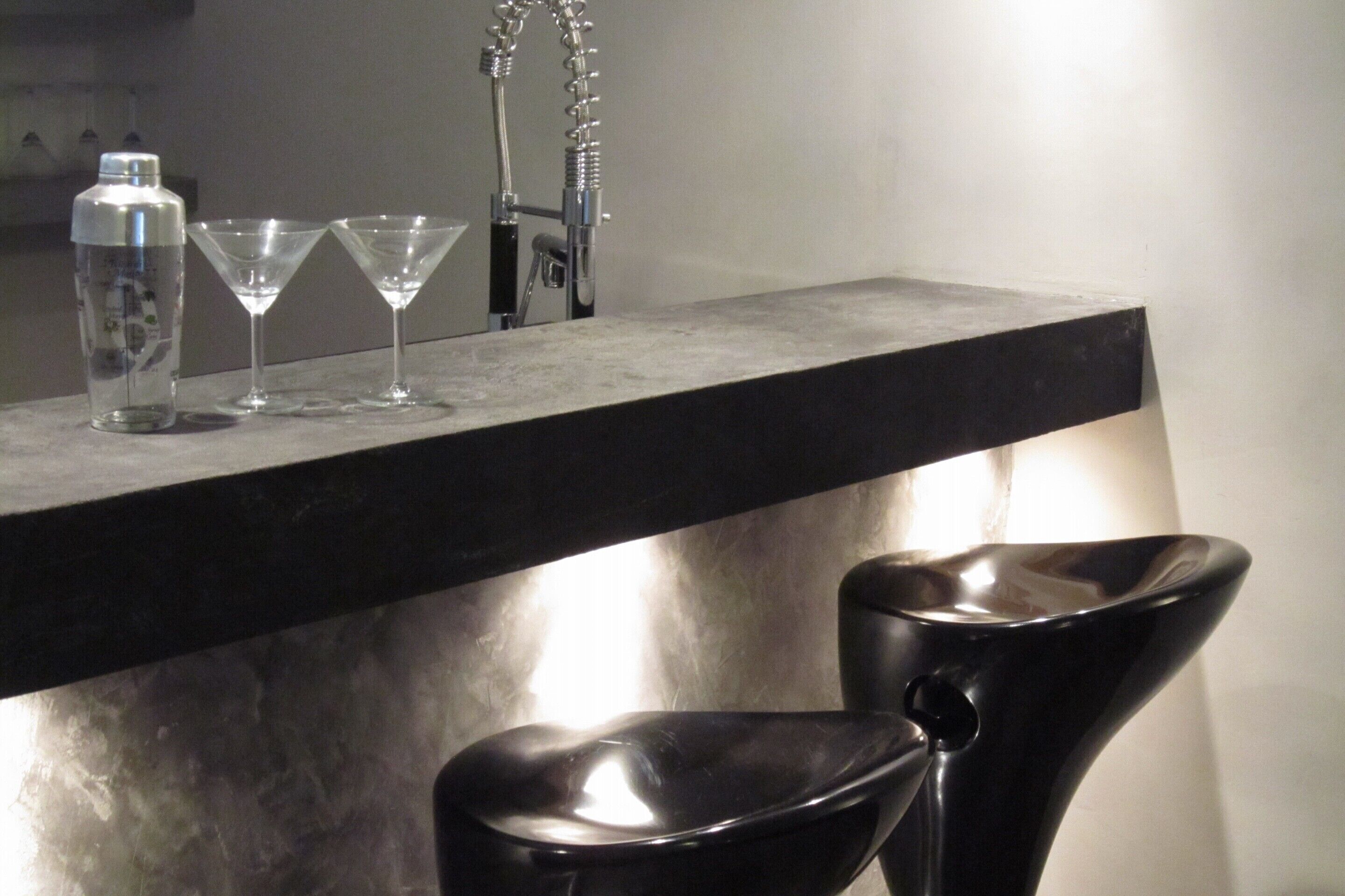A bar area with a countertop, a bottle, and two martini glasses.