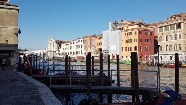 A waterfront view with a row of colorful buildings, a docked boat, and a clear blue sky. - Corte dei Bari (Venice)