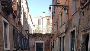 A narrow alleyway with stone pavement, flanked by buildings with metal railings and shutters. - Corte dei Bari (Venice)