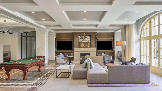 A spacious living area with a pool table, comfortable seating, a fireplace, and large windows.