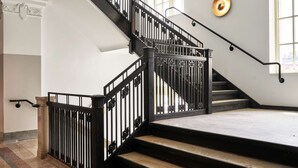 A staircase with black railings and a marble floor.