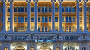 A grand hotel facade with classical architecture, featuring tall columns, ornate detailing, and a prominent entrance with a marquee.
