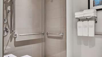A modern bathroom with a walk-in shower, grab bars, a towel rack, and a framed cityscape picture on the wall.