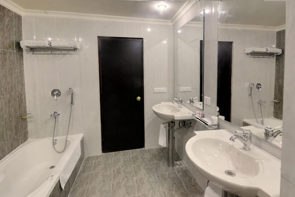 Uma casa de banho moderna com banheira, duas pias e um espelho grande.