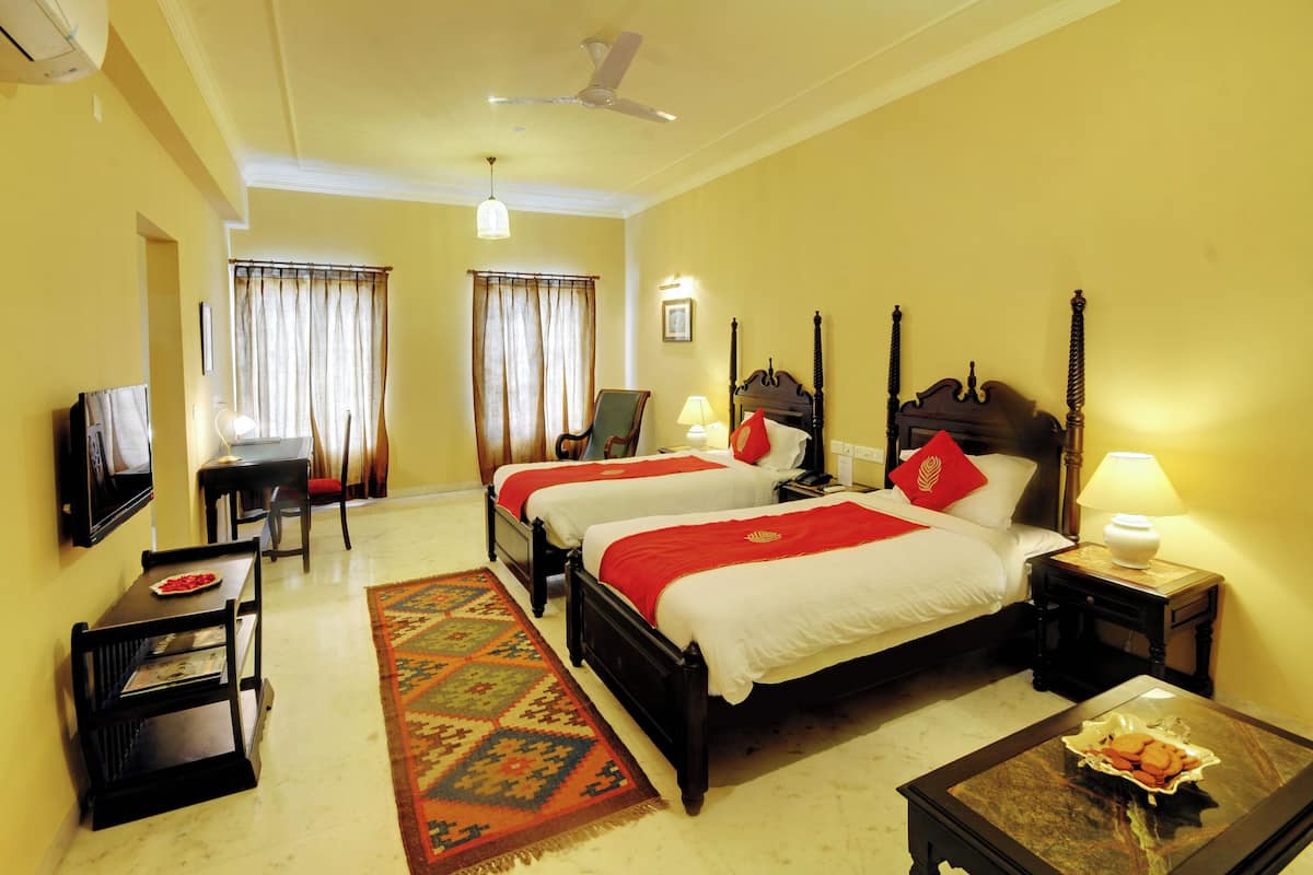 Quarto de hotel com duas camas, televisão, escrivaninha e uma cadeira.
