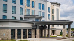 A modern hotel with a stone facade, large windows, and a covered entrance area. - Hyatt Place Altoona/Des Moines (Altoona)