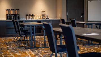 A conference room with a long table, chairs, a coffee station, and a whiteboard.