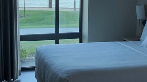 A hotel room with a large window offering a view of a body of water and a grassy area. - Hyatt Place Altoona/Des Moines (Altoona)